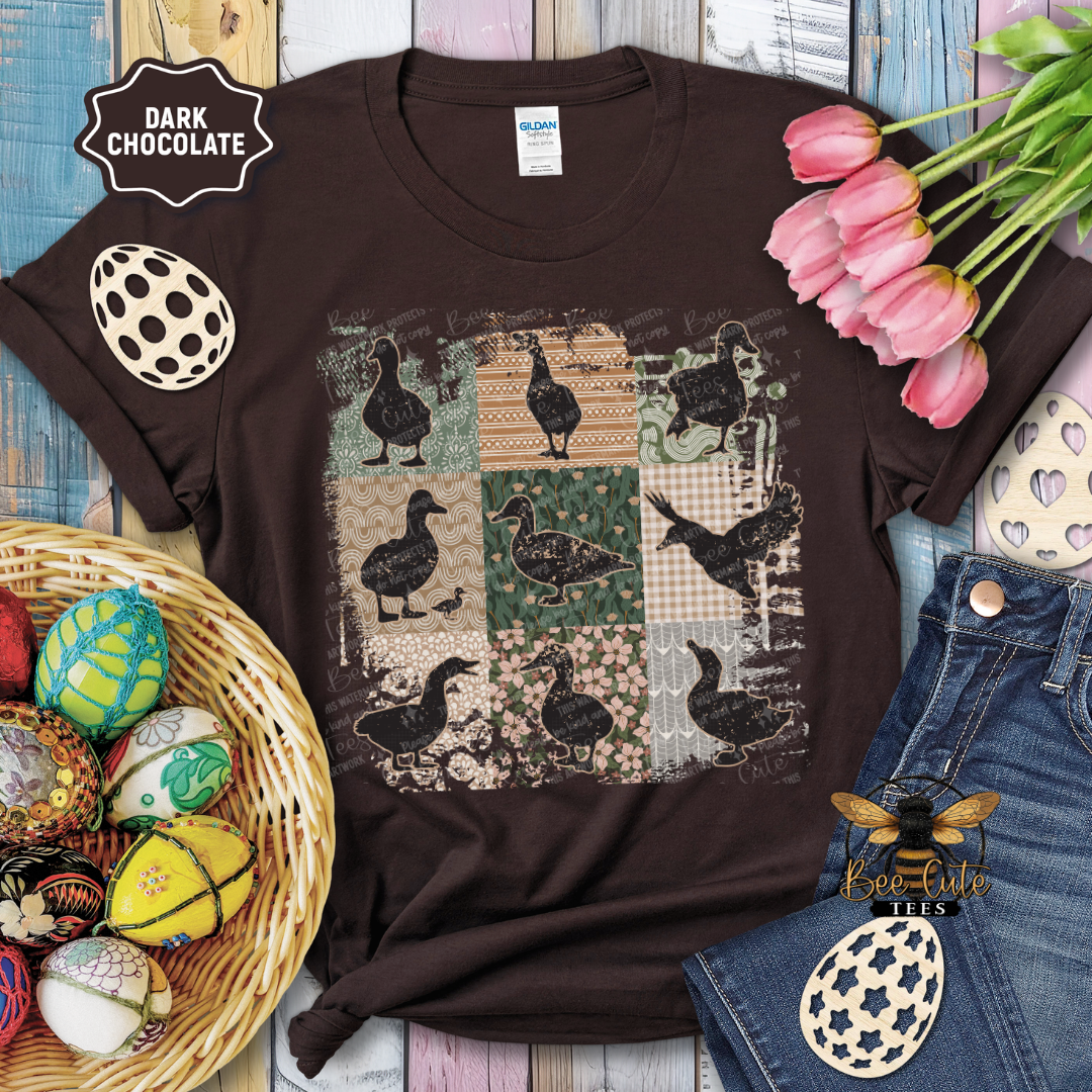 Brown t-shirt with duck pattern on a wooden surface with Easter decorations.
