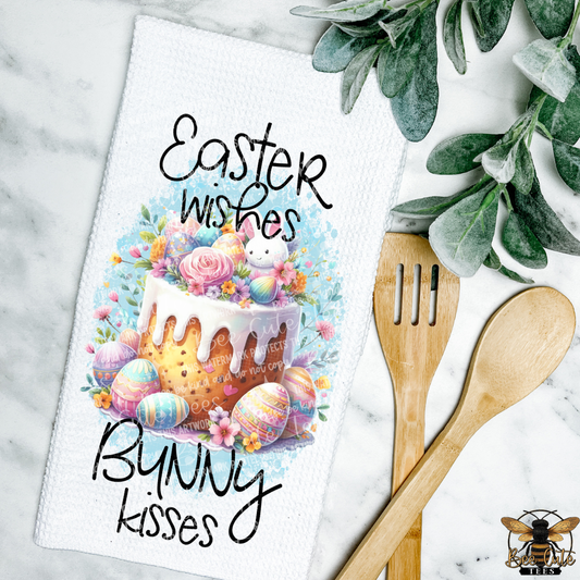 Easter-themed towel with cake and eggs design, wooden utensils, and greenery on a marble background.