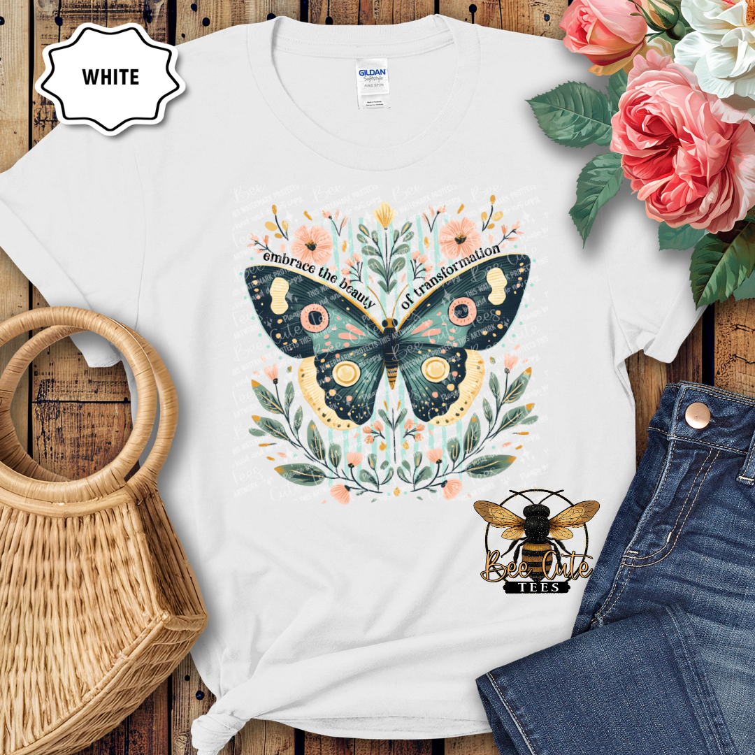 White t-shirt with butterfly design on a wooden surface with flowers and jeans.
