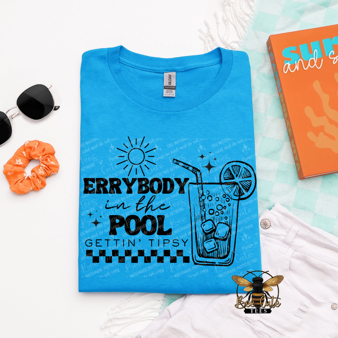 Blue t-shirt with pool-themed design on a white surface with accessories.