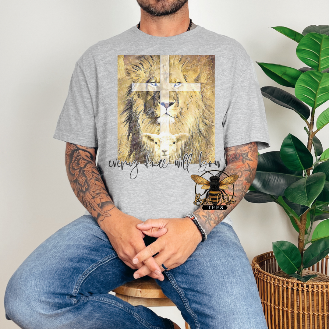 Person wearing a gray t-shirt with a lion and cross design, sitting next to a plant.