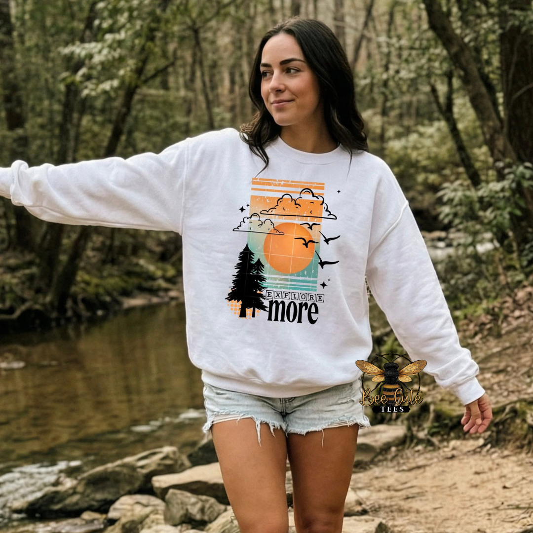 Woman wearing a white sweatshirt with a nature-themed design in a forest setting