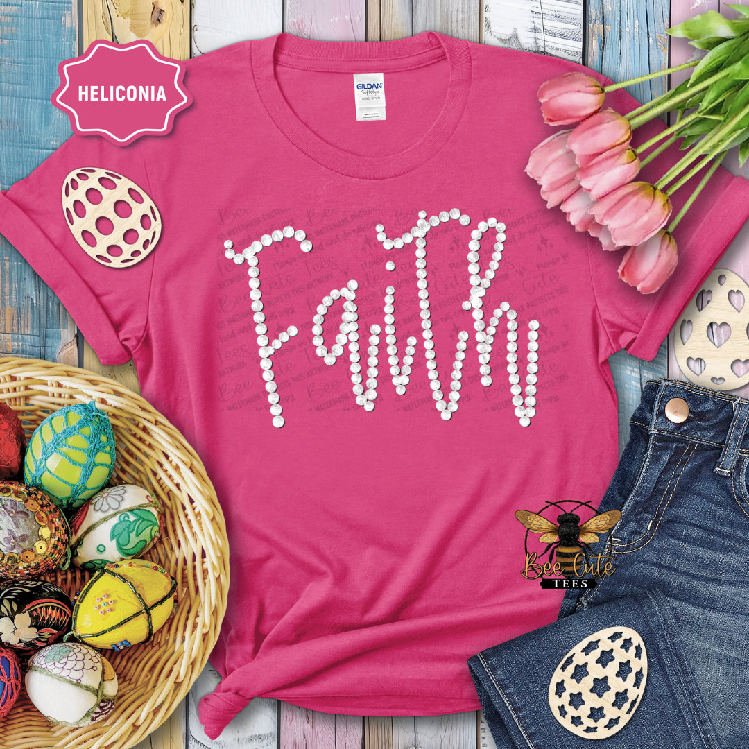 Pink t-shirt with 'Faith' design, Easter eggs, and tulips on a wooden surface.