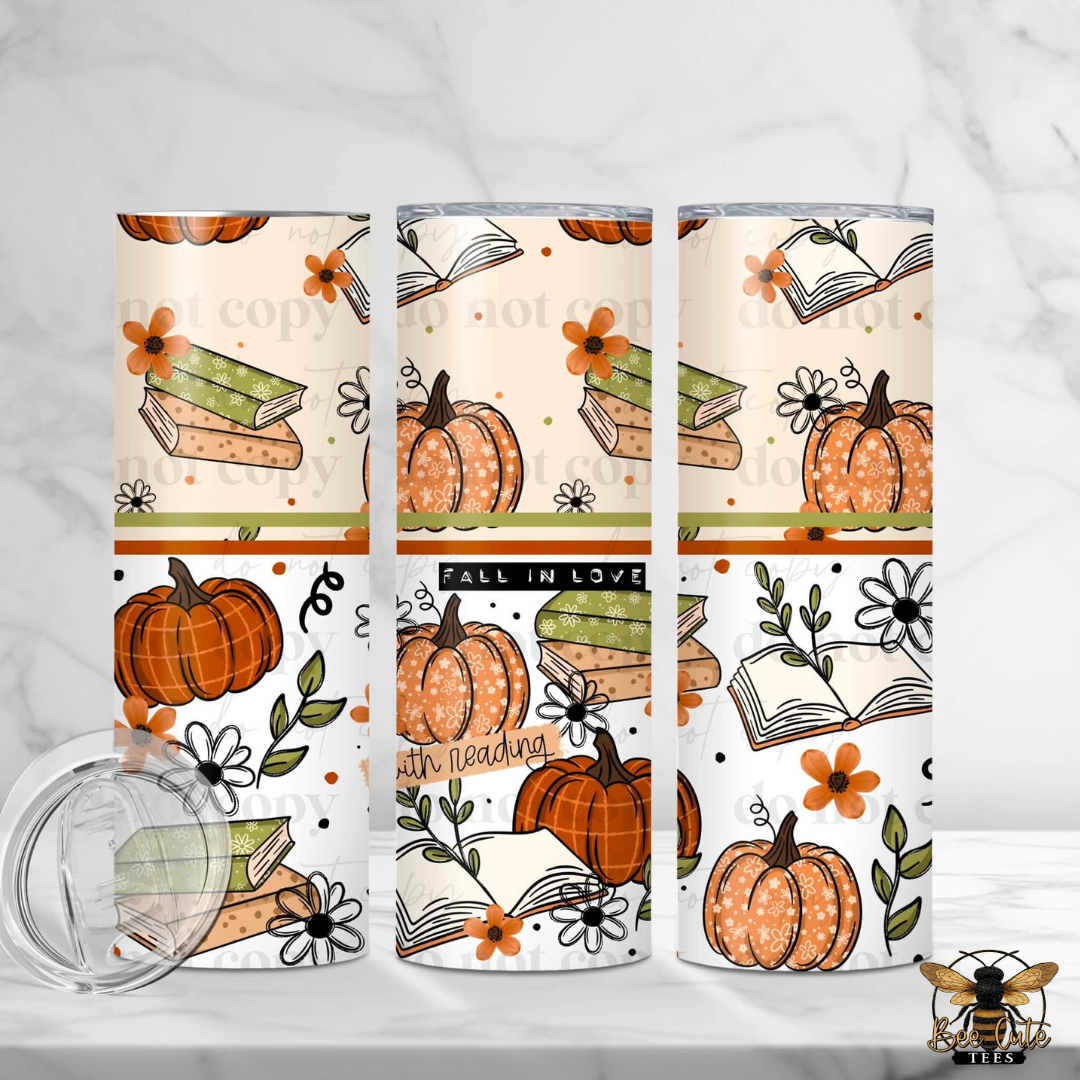 Three insulated tumbler cups with a fall-themed pattern of pumpkins, open books, flowers, and leaves, shown on a light marble background with a clear lid in the foreground.