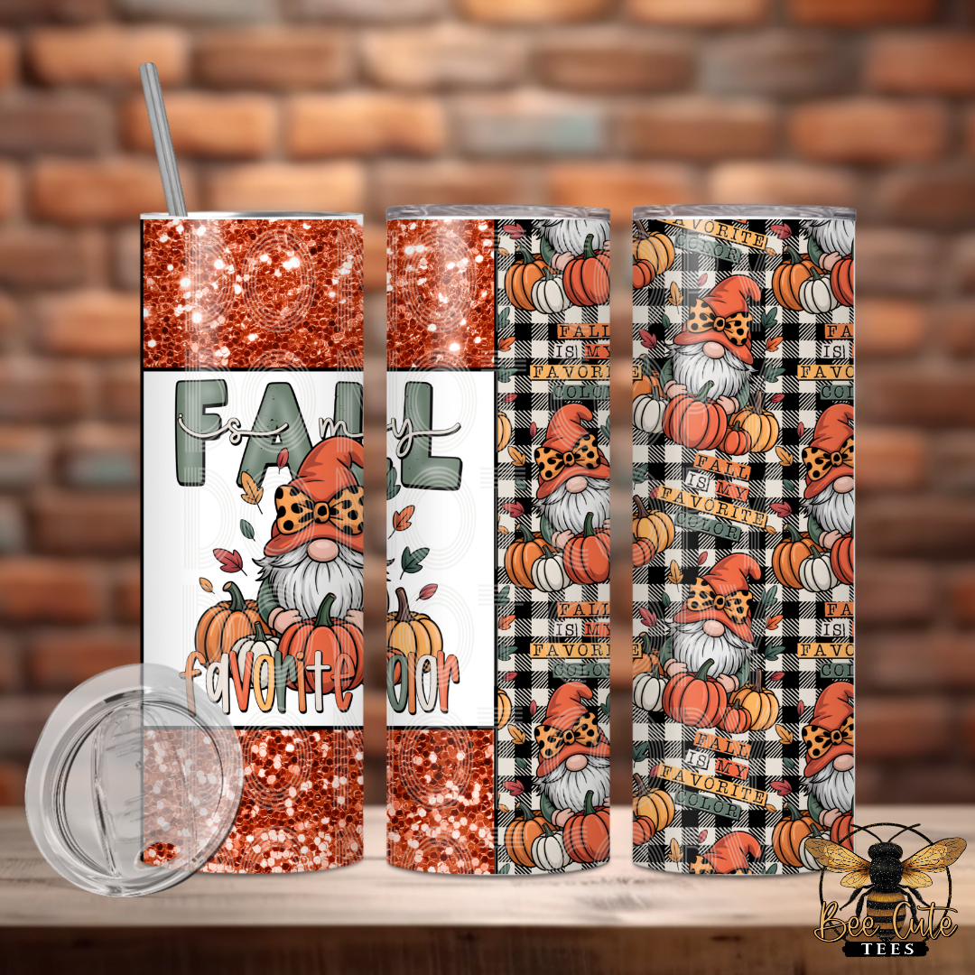 Three insulated tumblers with a fall gnome and pumpkin print are displayed on a wooden surface against a brick wall background. A clear lid is shown in the lower left.