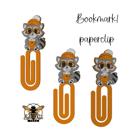 Three cartoon paperclip bookmarks featuring a gray and white raccoon wearing an orange beanie and glasses, with the word 'Bookmark' and 'paperclip' text on a white background. A small bee logo with 'BEE' appears in the lower left.