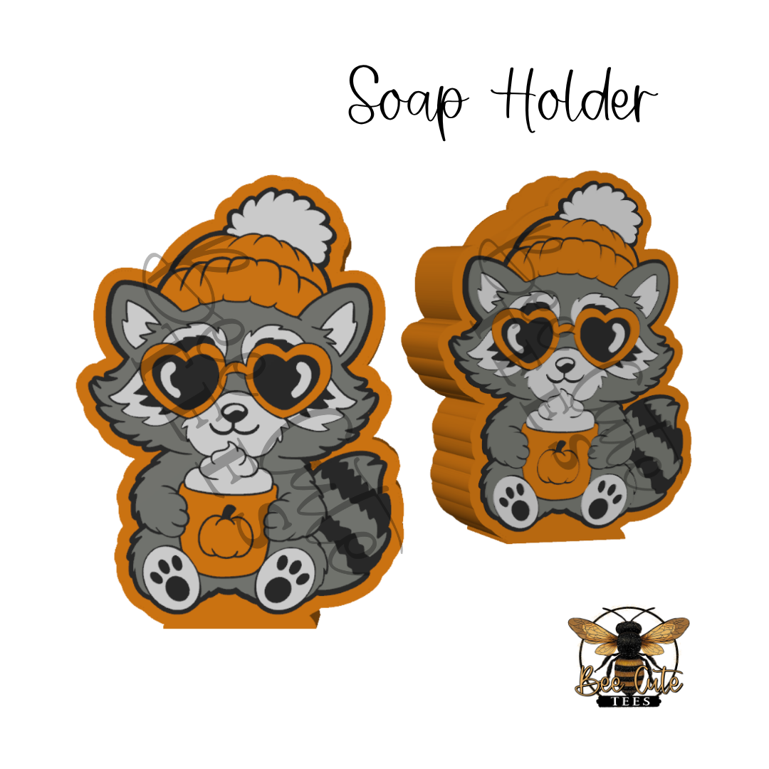 Two Halloween-themed soap holder ornaments shaped like raccoons wearing orange bunnies, heart-shaped sunglasses, and holding pumpkins, shown on a white background with 'Soap Holder' text and a bee logo.