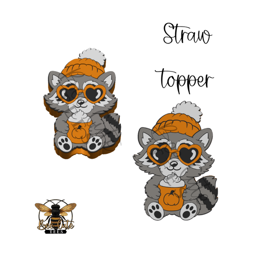 Two cartoon raccoon graphics wearing an orange knit beanie with a white pom-pom, heart-shaped sunglasses, and an orange pumpkin cup, shown on a white background with the words 'Straw topper' and a small bee logo.