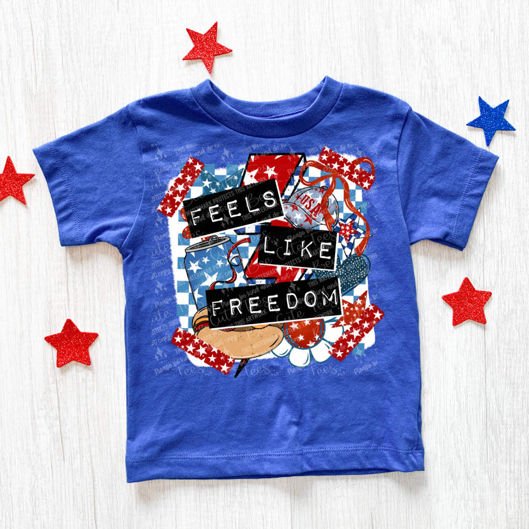 Blue t-shirt with 'Feels Like Freedom' graphic design on a white background with decorative stars.