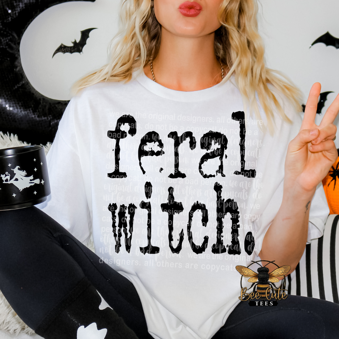 Person wearing a white t-shirt with 'feral witch' text, surrounded by Halloween decorations.