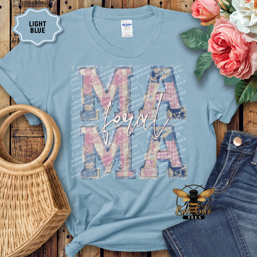 Light blue t-shirt with 'MAMA' design on a wooden surface with flowers and denim jeans.