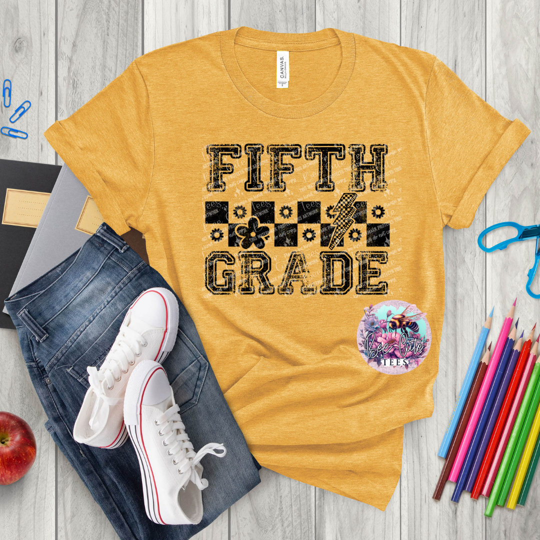 Yellow t-shirt with 'Fifth Grade' text on a wooden surface with jeans, sneakers, and school supplies.