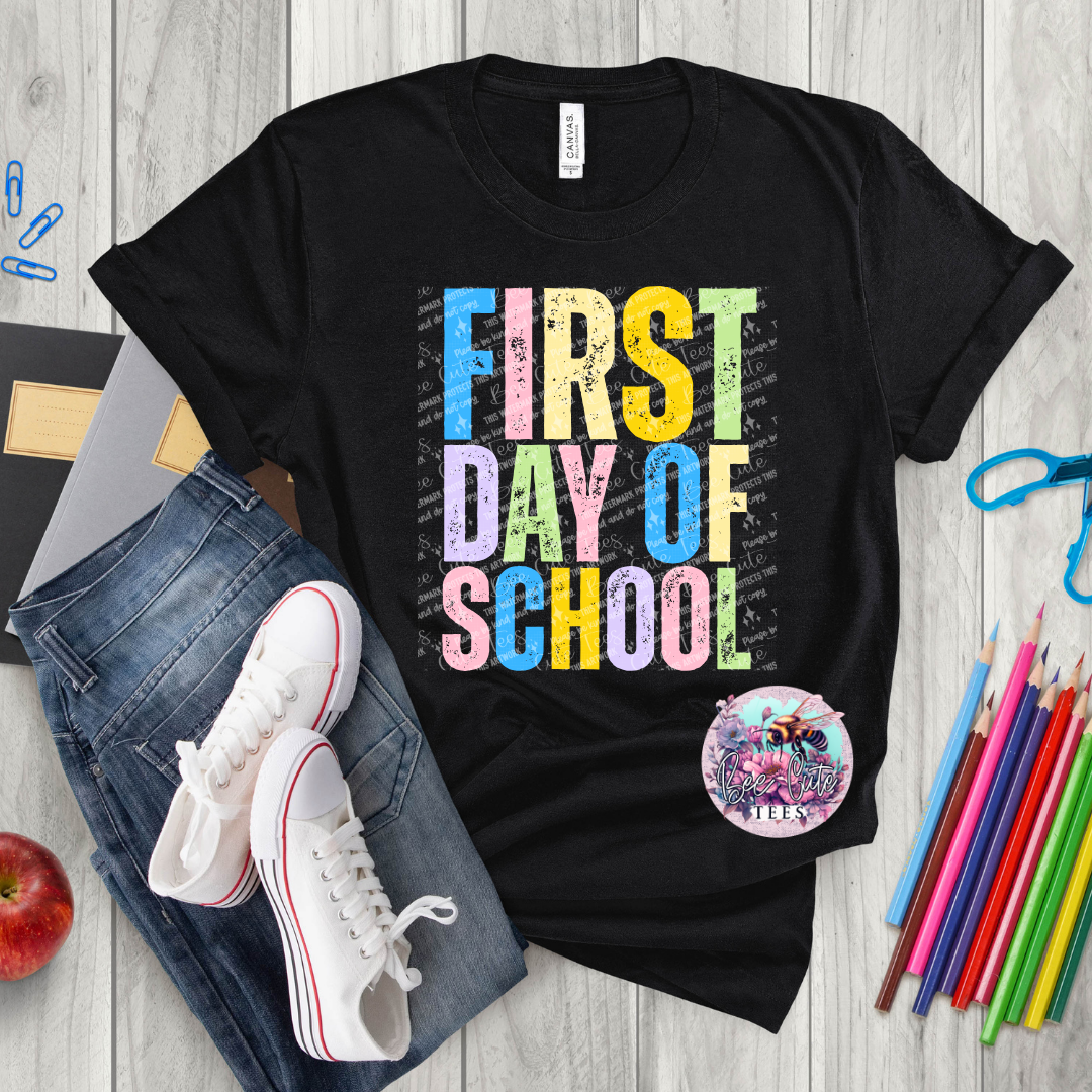 Black t-shirt with 'First Day of School' text, jeans, sneakers, and school supplies on a wooden surface