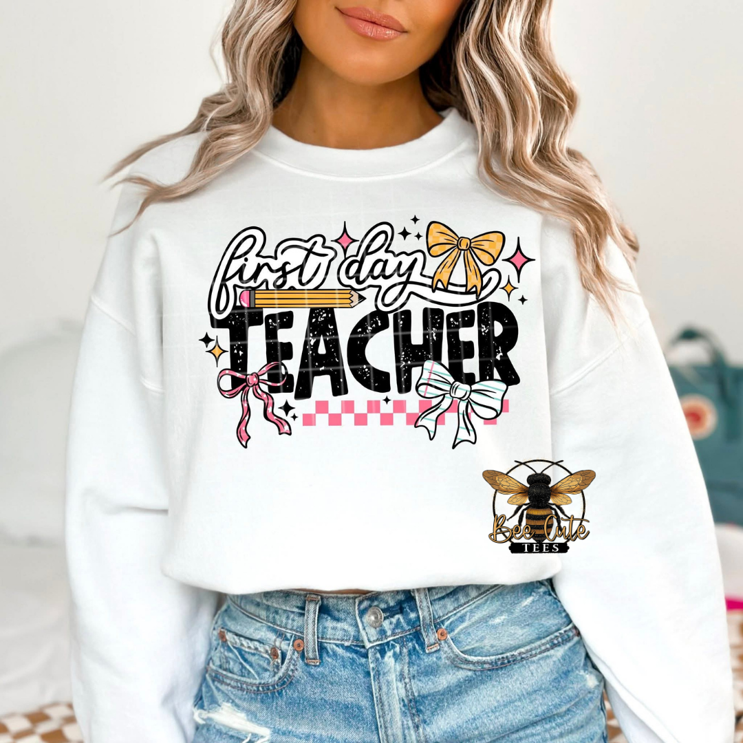 Person wearing a white sweatshirt with 'first day teacher' text and graphics.