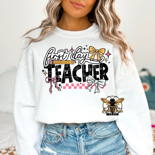 Person wearing a white sweatshirt with 'first day teacher' text and graphics.