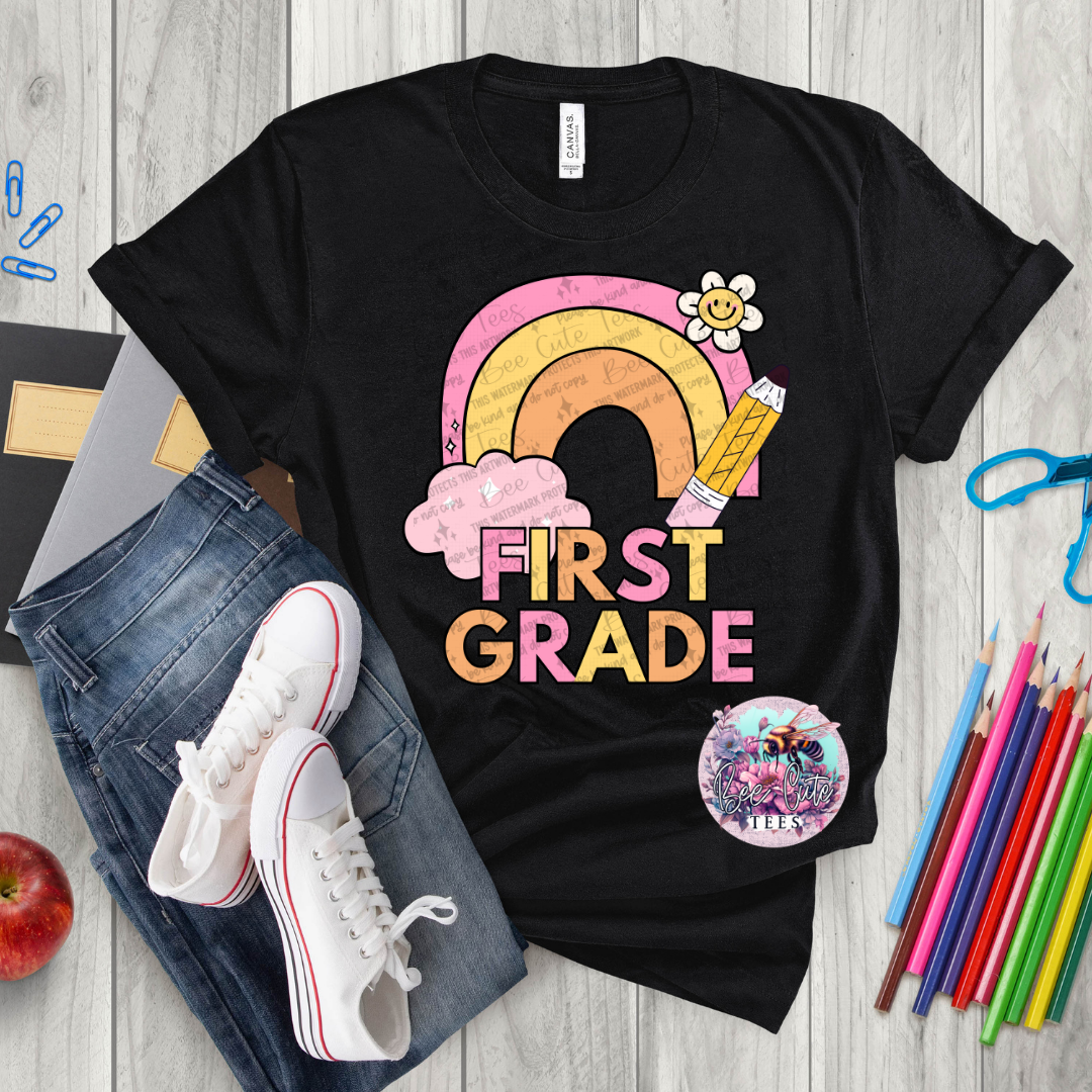 Black t-shirt with 'First Grade' design on a wooden surface with school supplies.