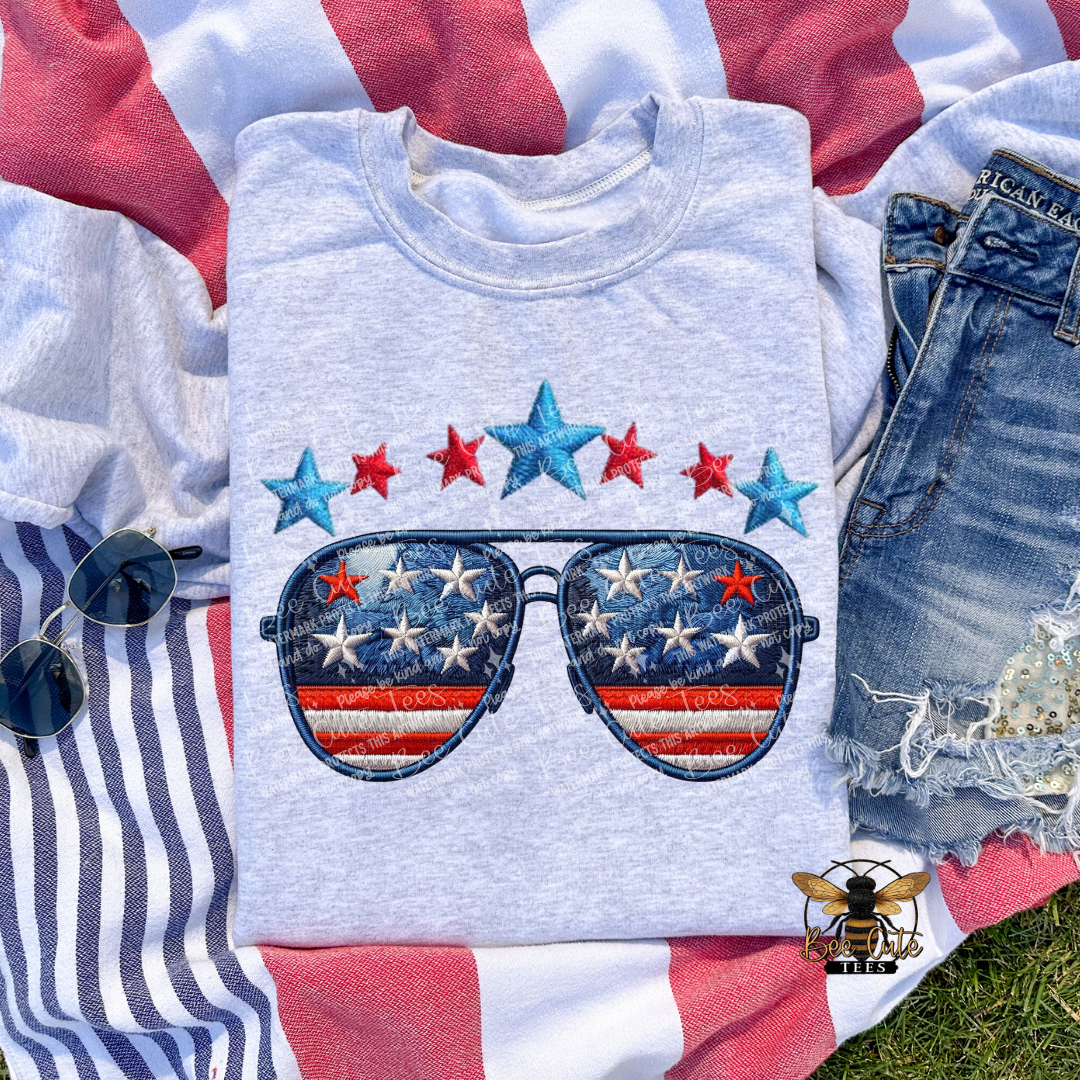 Gray sweatshirt with sunglasses and star design on a red, white, and blue background