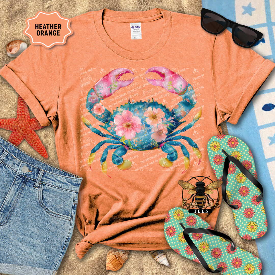 Coral t-shirt with a colorful crab design, sunglasses, jeans, starfish, and flip-flops on a beach-themed background.