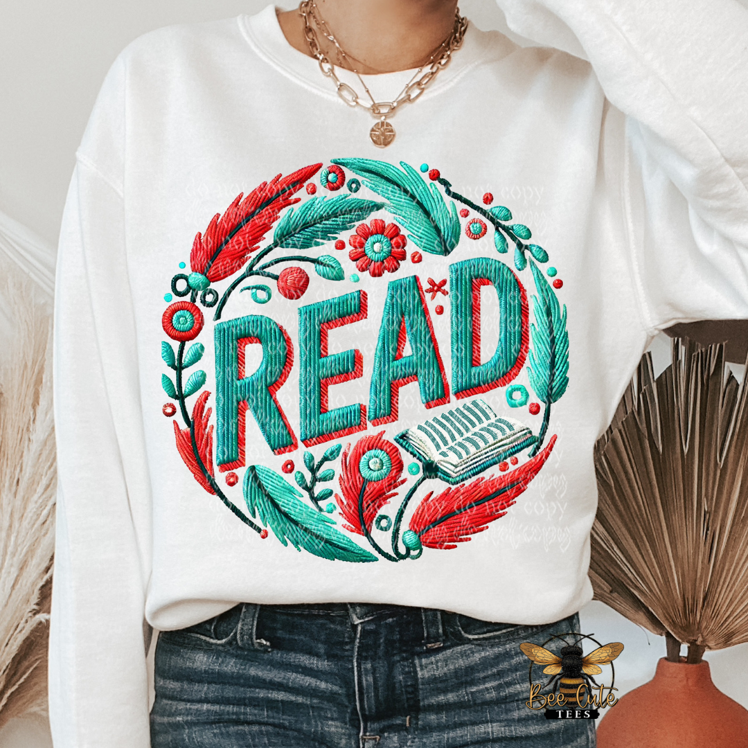 White sweatshirt with colorful 'READ' design and feathers, worn by a person.