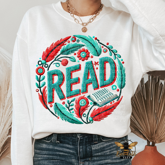 White sweatshirt with colorful 'READ' design and feathers, worn by a person.