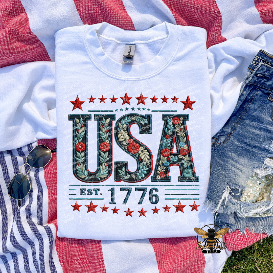 White t-shirt with 'USA EST. 1776' design on a flag background