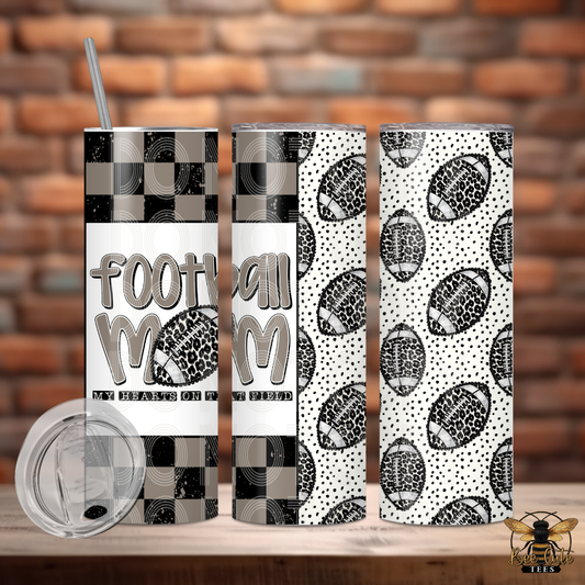 Three views of a stainless steel skinny tumbler with a clear lid and straw, featuring a black and white football-themed design with the text 'football mom' and football motifs, displayed on a wooden surface against a brick wall background.