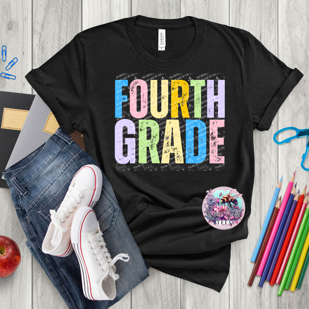 Black t-shirt with 'FOURTH GRADE' in colorful letters, surrounded by jeans, sneakers, an apple, and school supplies on a wooden surface.