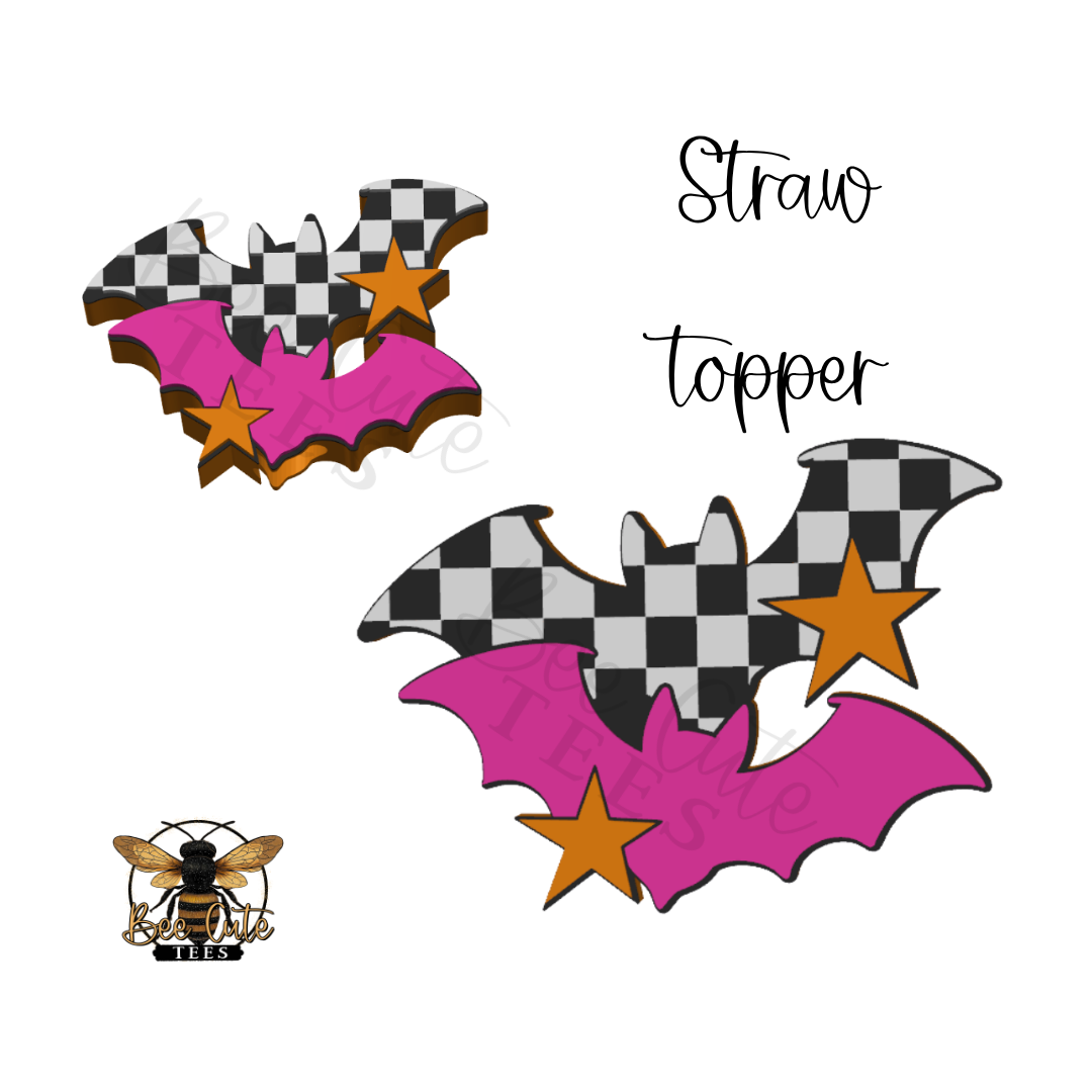 Two Halloween straw toppers shaped like bats, featuring a black and white checkered body, bright pink wings, and orange stars, shown on a white background with the text 'Straw topper' and a bee logo.