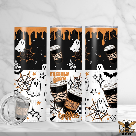 Three tall insulated tumblers with Halloween-themed wraps are shown on a light marble surface and background. The designs feature black and white sections with orange accents, including ghosts, spiderwebs, stars, coffee cups, and the words 'FRESHLY Boo'D coffee.