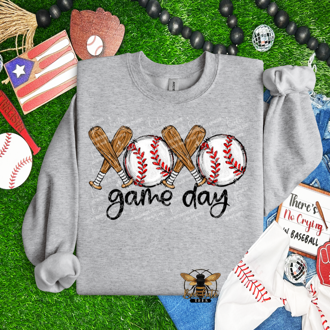 Gray sweatshirt with baseball-themed design on a grass background with sports-themed items.