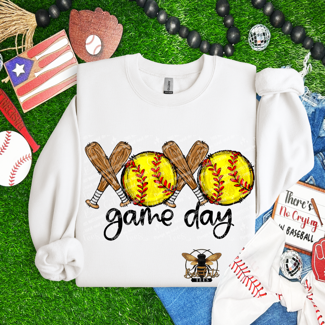 White sweatshirt with softball and bat design on a grass background with sports-themed accessories.