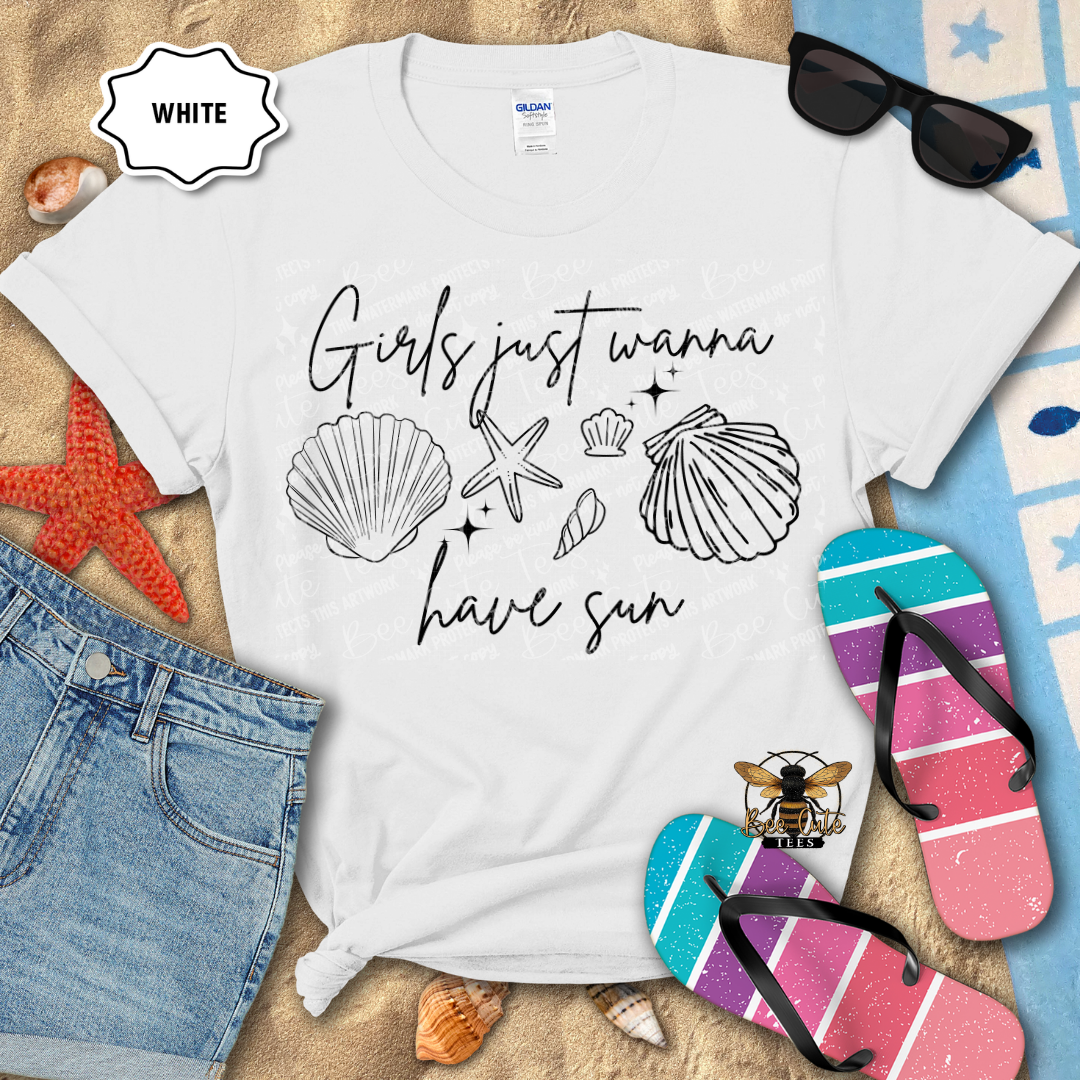 White t-shirt with 'Girls just wanna have sun' text and beach-themed graphics on a sandy background with flip-flops and sunglasses.