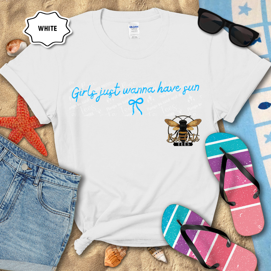 White t-shirt with 'Girls just wanna have sun' text and bee logo, surrounded by beach accessories.