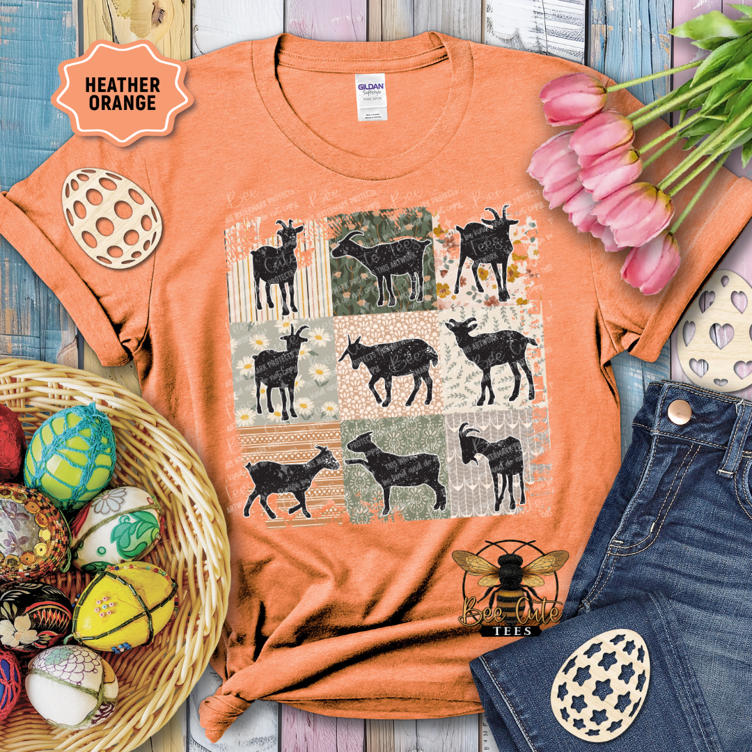 Orange t-shirt with goat pattern, surrounded by decorative items on a wooden surface.