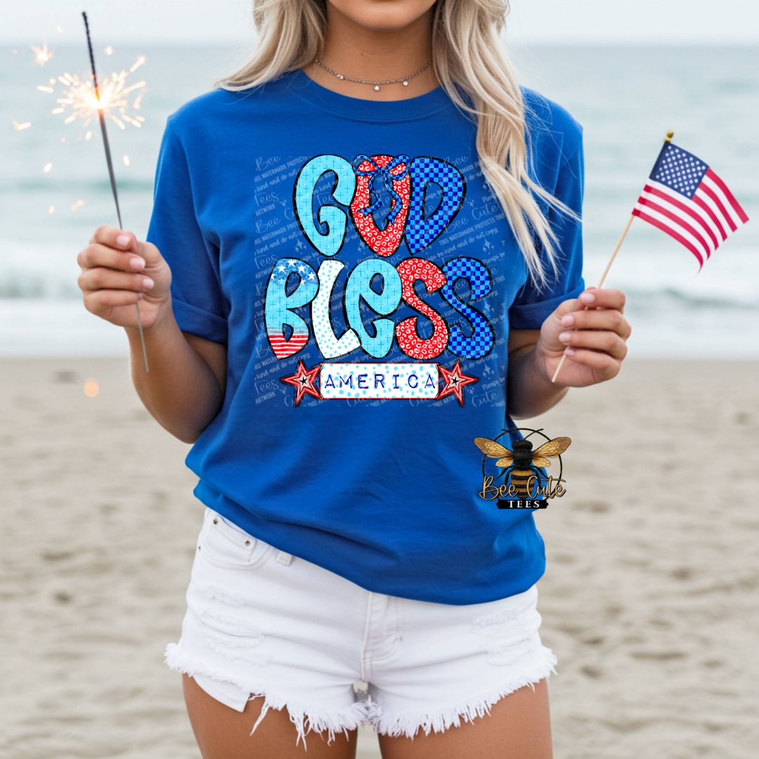 Person wearing a blue t-shirt with 'God Bless America' on a beach
