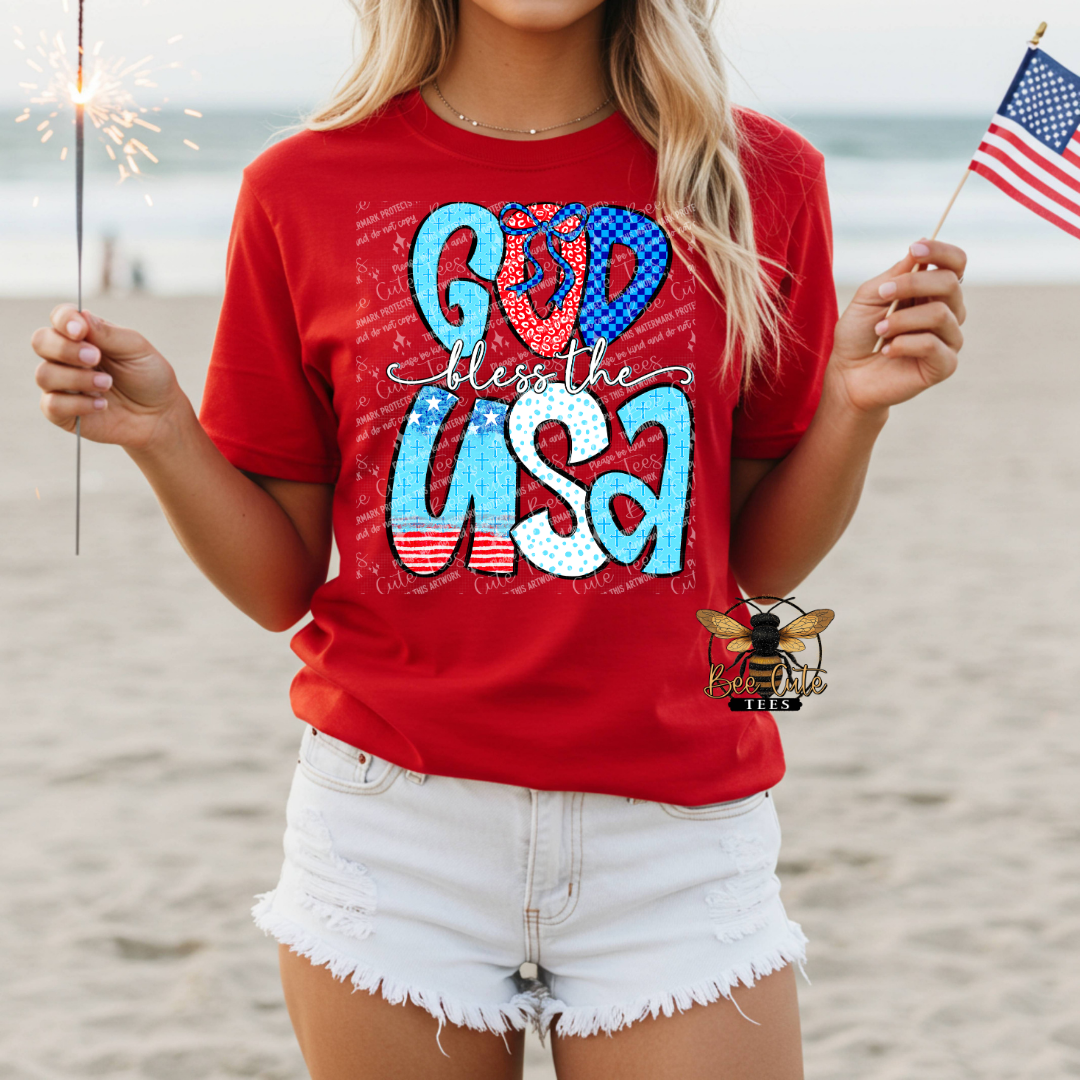 Person wearing a red 'God bless the USA' t-shirt on a beach.
