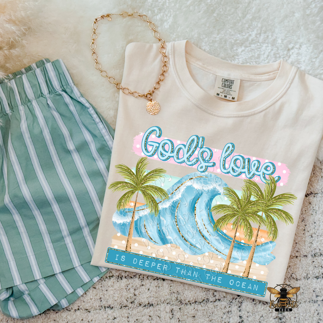 Beige t-shirt with tropical design and text, green shorts, and necklace on a textured surface