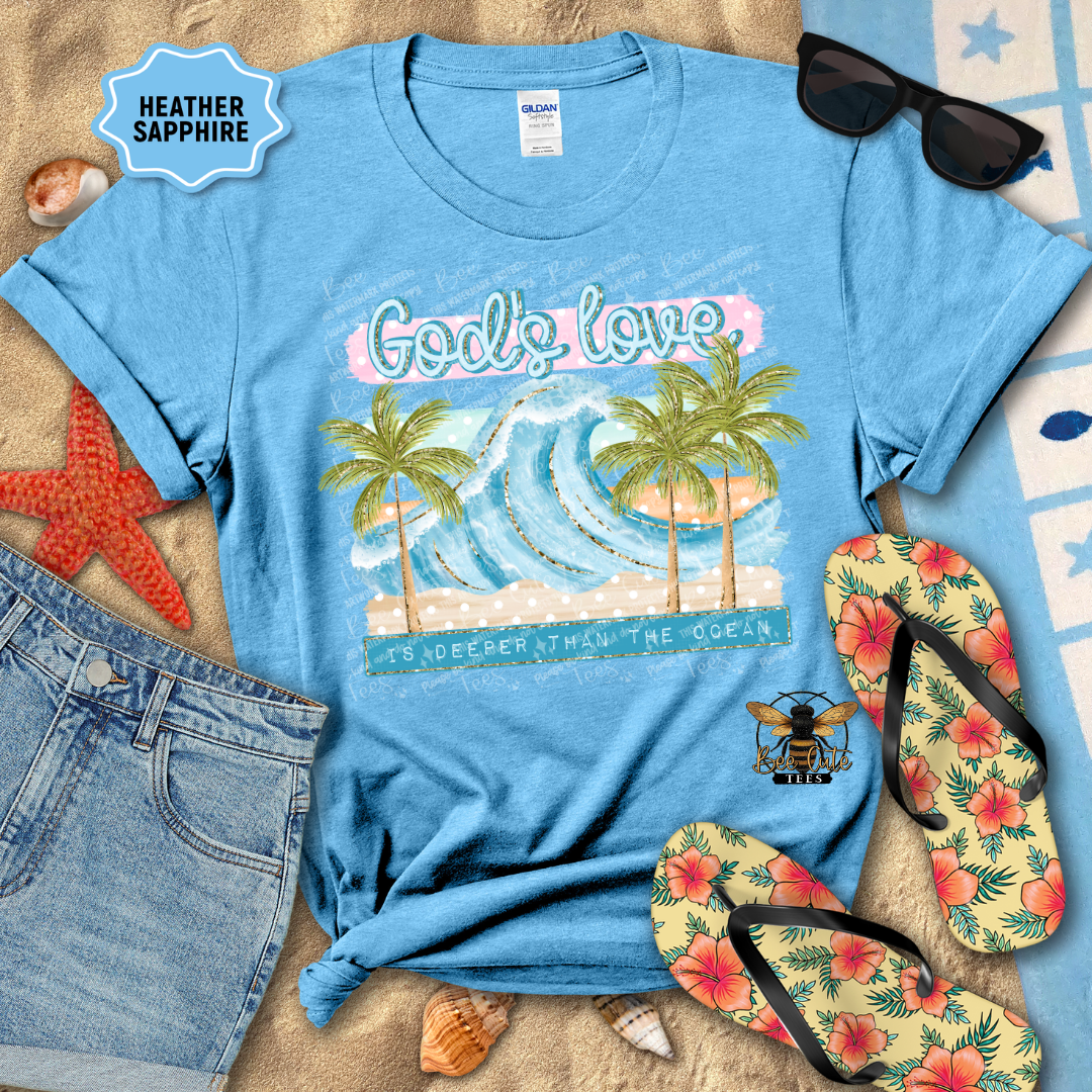 Blue t-shirt with beach graphic and text, sunglasses, flip-flops, and denim shorts on a sandy background.