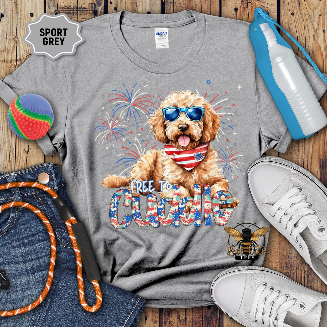 Gray t-shirt with a dog graphic and 'Free to Cuddle' text on a wooden surface with accessories.
