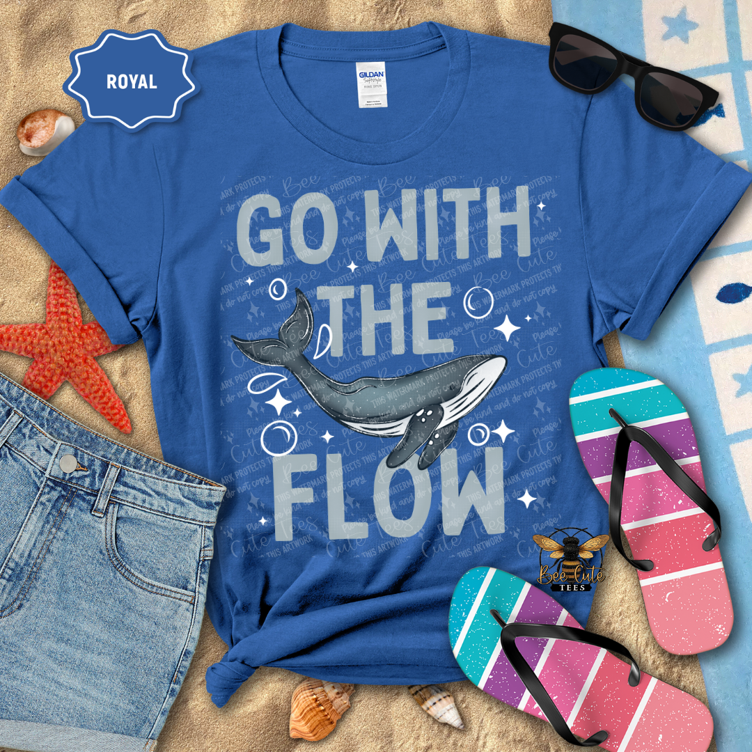 Blue t-shirt with whale graphic and 'Go with the Flow' text, surrounded by beach accessories.
