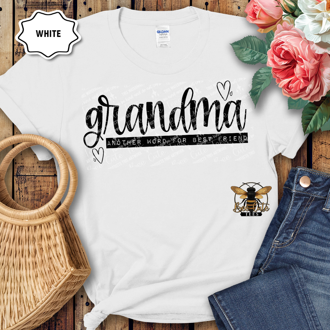 White t-shirt with 'grandma another word for best friend' text, surrounded by flowers and denim jeans on a wooden surface.
