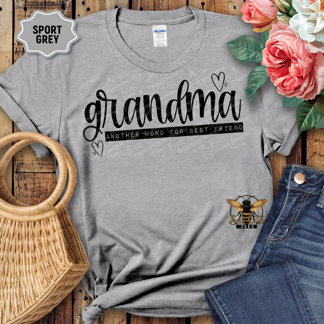 Gray t-shirt with 'grandma another word for best friend' text, placed on a wooden surface with flowers and jeans.