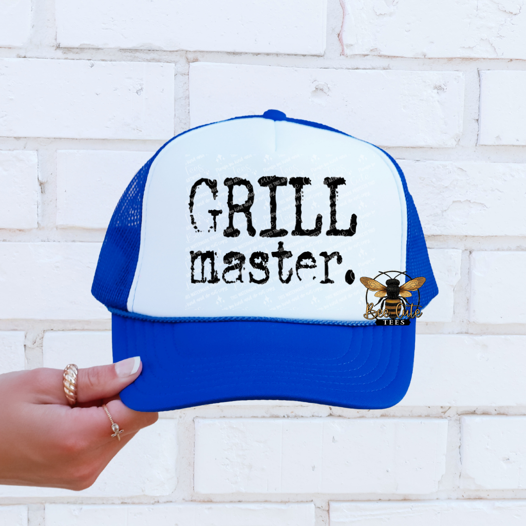 Blue and white cap with 'GRILL master.' text and bee logo, held against a white brick wall.