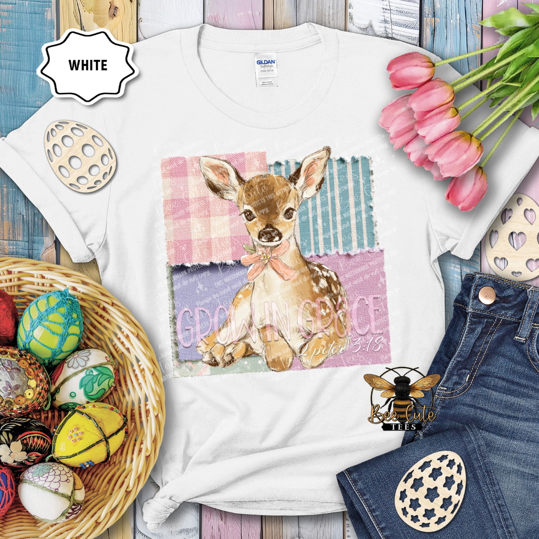White t-shirt with a deer graphic and text, surrounded by Easter decorations on a wooden surface.