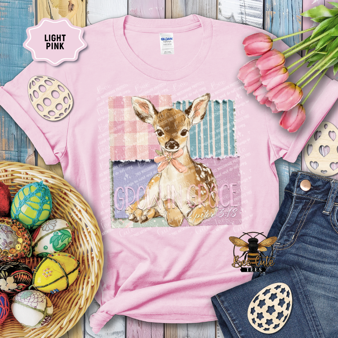 Pink t-shirt with a deer graphic and Easter decorations on a wooden surface