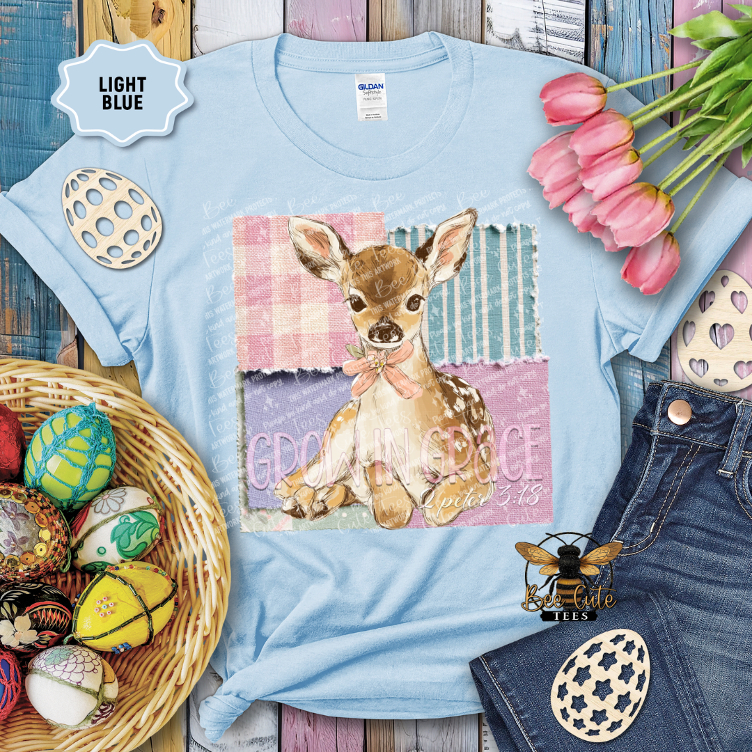 Light blue t-shirt with a deer graphic and text, surrounded by Easter decorations on a wooden surface.
