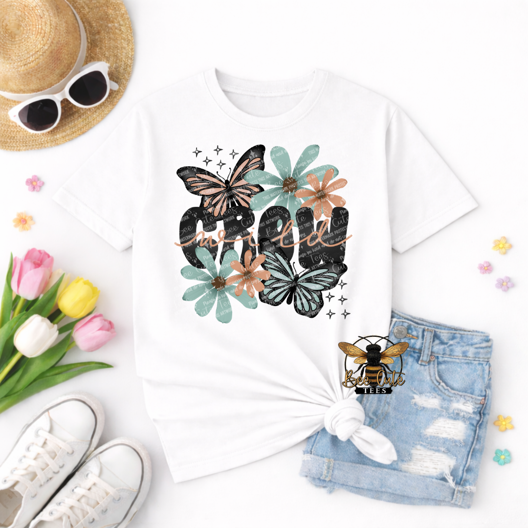 White t-shirt with floral and butterfly design, sunglasses, tulips, sneakers, and denim shorts on a white background.