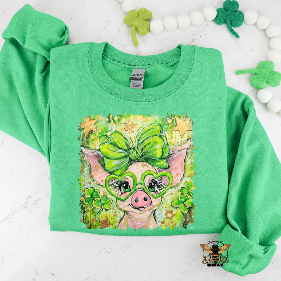 Green sweatshirt with a pig wearing glasses and a bow design on a white background with shamrocks.