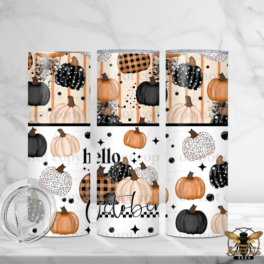 Three insulated tumblers with a fall harvest pattern featuring pumpkins, plaid, and the words 'Hello October' are displayed on a white marble surface with a clear lid in the foreground.