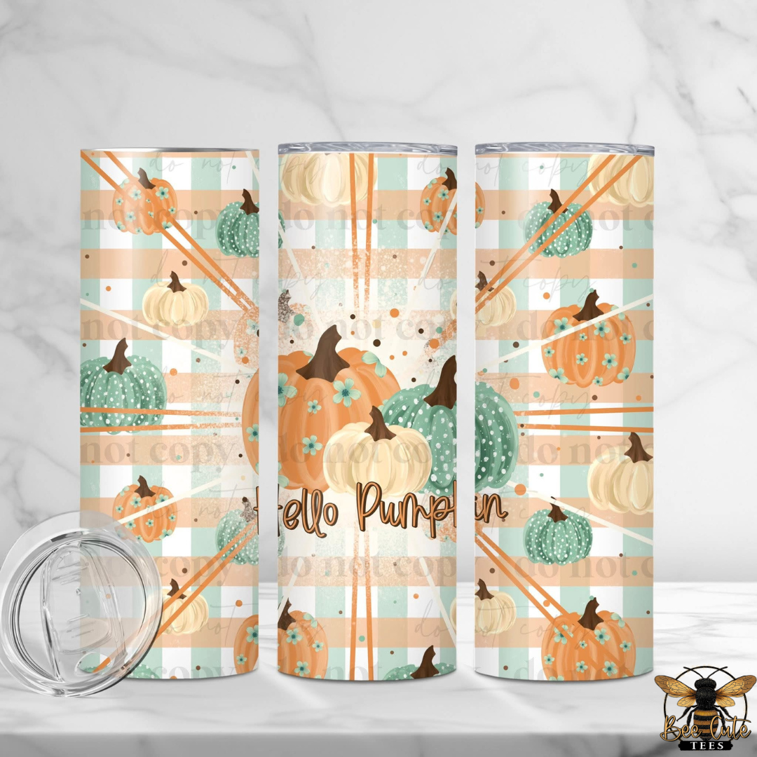 Three tall insulated tumblers with a fall pumpkin print are displayed on a white marble surface, with a clear lid shown in the lower left. The tumblers feature orange and cream pumpkins, teal and cream sunflowers, and the words 'Hello Pumpkin' in brown script.